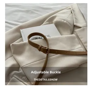 Close-up of tan PU leather belt with a minimalist metal buckle on a beige blazer