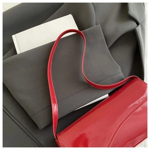 Detail of red patent leather shoulder bag showing glossy texture and fine stitching