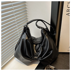Detail of a black PU leather tote bag with large bow-knot pleats in a window setting