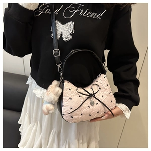 Détail d'un sac jacquard rose avec nœud noir, breloque cœur et pendentif lapin peluche
