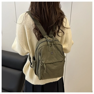Detail of army green nylon backpack showing fabric texture and adjustable shoulder straps