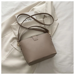 Détail d'un sac seau en cuir grainé taupe avec des ferrures dorées élégantes