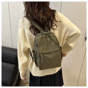 Olive green Oxford cloth backpack shown from the back featuring a metal logo detail