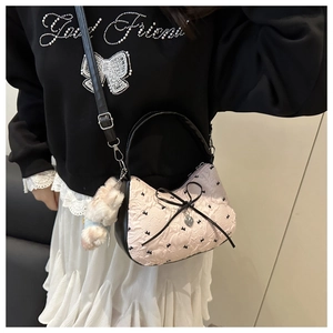 Detail of pink jacquard handbag featuring black bow embroidery and heart pendant
