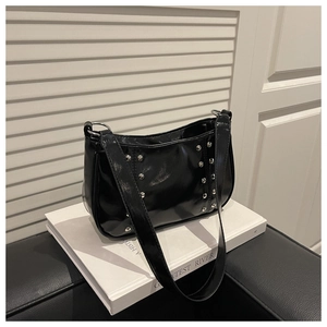 Detail of silver rivets on black patent leather shoulder bag with vintage rock style