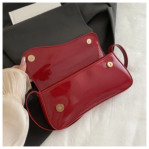 Detail view of red patent leather shoulder bag showing magnetic buckle closure and lining
