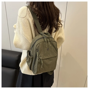 Rear view of a model wearing the olive green nylon crossbody bag with side drawstring pocket