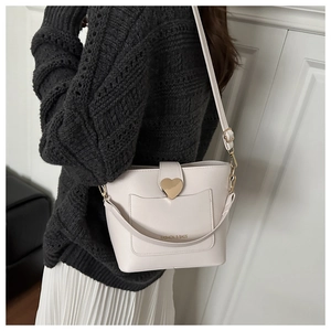 Détail du sac seau crème avec fermoir coeur doré et logo fashion gaufré élégant