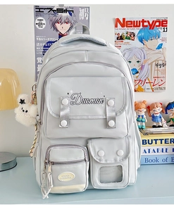 Close-up of light grey multi-pocket school backpack with cute plush charm and logo