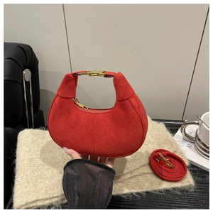 Detail of red frosted suede moon bag with golden hardware on a soft scarf background