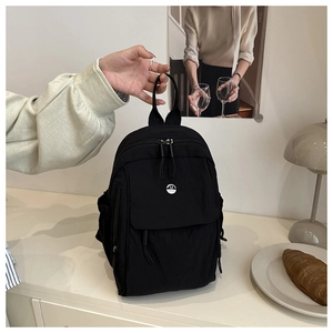 Close-up of black nylon mini backpack with silver M logo and front zippered pocket