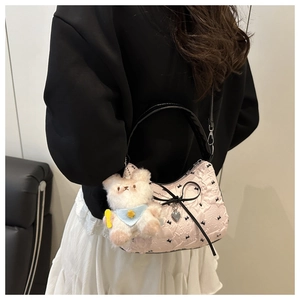 Detail of pink polka dot bag with black bow, heart charm and plush bear accessory