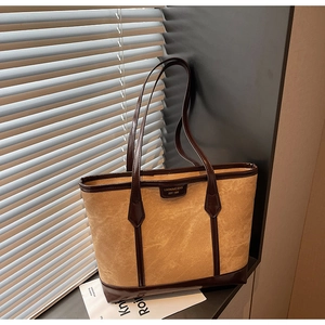 Détail du sac cabas en toile camel montrant la plaque vintage et les lanières en cuir
