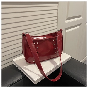 Detail of red patent leather shoulder bag featuring silver metallic stud accents