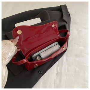 Detail view of red glossy patent leather crossbody bag with magnetic closure and interior