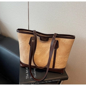 Gros plan sur un sac cabas vintage camel avec anses café foncé et logo de la marque
