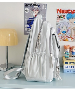 Detailed view of the water bottle side pocket and zippers on a light grey nylon backpack