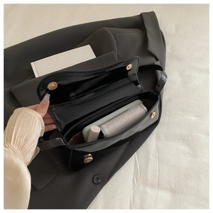 Detail view of the spacious glossy black patent leather bag interior with magnetic closures