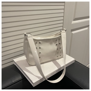 Macro view of white faux leather shoulder bag featuring stylish silver round rivets