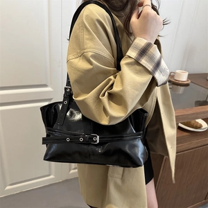 Glossy black patent leather tote bag with belt buckle detail shown on shoulder