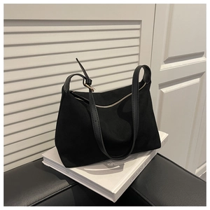 Close-up of black canvas shoulder bag with golden metal zipper and leather strap detail