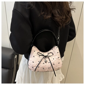 Detail of pink crescent bag with floral texture, black bow, and heart pendant detail