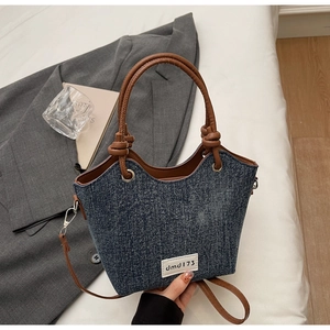 Dettaglio della borsa a secchiello in denim blu con manici in similpelle marrone