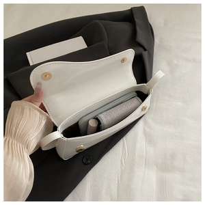 Interior view of white patent leather crossbody bag showing phone and lipstick storage