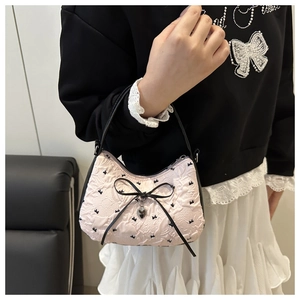Détail du sac hobo en jacquard rose avec nœuds noirs et pendentif en cœur