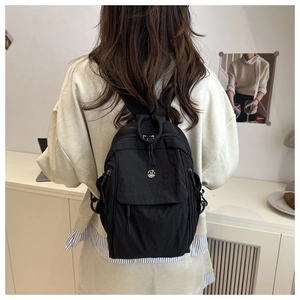 Rear view of model wearing a black mini oxford backpack with round metal M plaque