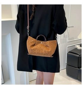 Detail of leopard print tote bag with thin straps and silver magnetic closure on a model