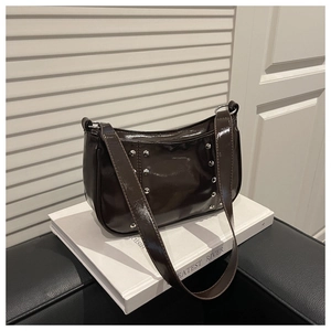Detail of dark brown patent leather shoulder bag with silver studs and wide strap