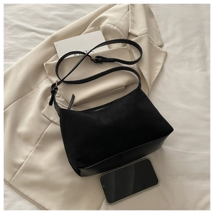 Detail view of black matte suede hobo bag with smooth leather base on beige blazer