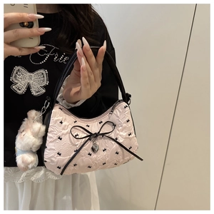 Détail du sac à main rose avec motifs nœuds noirs et pendentif lapin en peluche