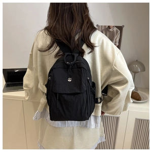 Black oxford backpack on female model back showing dual straps and metal logo