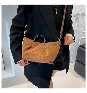 Detail of leopard print tote bag with brown leather handles and silver metal buckle