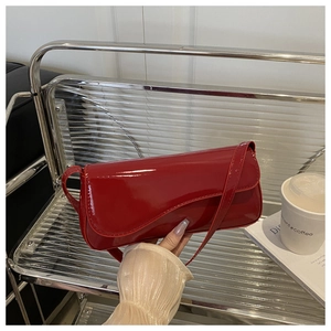 Close-up of glossy red patent leather shoulder bag with sleek rectangular flap design