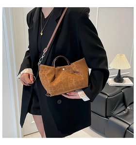 Detailed close-up of brown leopard print suede bag with round handles and metal clasp