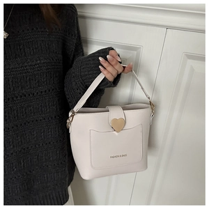 Détail du sac seau en cuir crème avec fermoir cœur doré et inscription logo chic