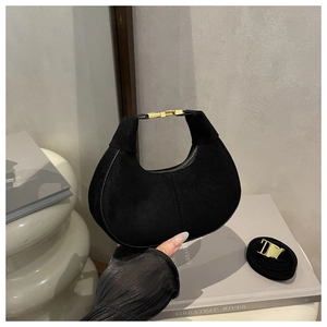 Detail of black suede crescent bag featuring gold metal buckle and detachable shoulder strap