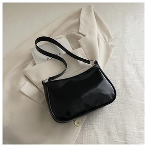 Detail of black glossy leather shoulder bag with silver rings on a neutral background