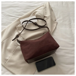 Detail of vintage matte burgundy shoulder bag resting on a beige blazer background