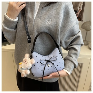 Détail du sac rayé bleu clair avec motifs de cœurs noirs et charm de lapin en peluche
