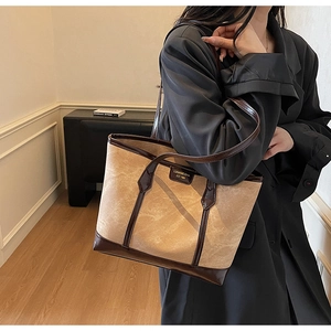 Modèle portant un grand sac cabas en toile avec bordures et anses en cuir marron