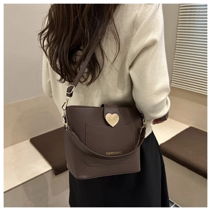 Detail of dark brown lychee leather bucket bag with gold heart buckle and wide strap