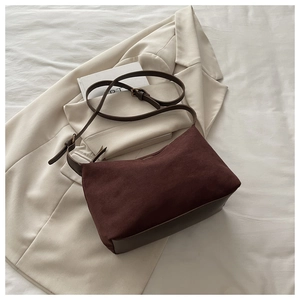Detail of burgundy faux suede and brown leather texture on a vintage crossbody bag