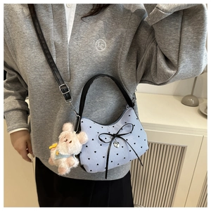 Detail of blue striped crossbody bag with black bow and pink plush bunny charm