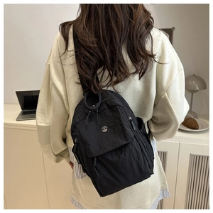 Detail of a black nylon crossbody bag with metal M logo and multiple zipper pockets