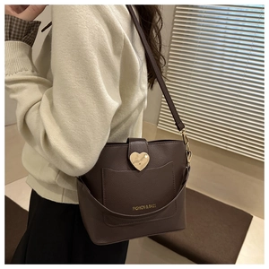 Detail of dark brown bucket bag with lychee texture and heart-shaped golden buckle