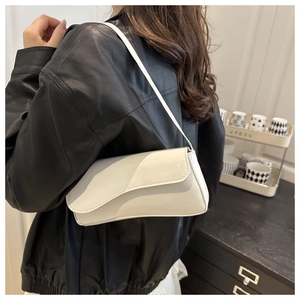 Close-up of stylish white glossy shoulder bag worn with a black leather jacket